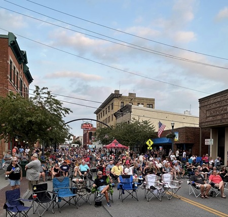 Delaware County Festival A large crowd is gathered in the middle of a downtown street in Delaware County under sunny skies for a summer concert