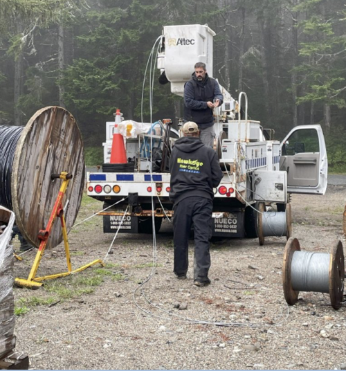 A crew of two workers at back of work truck getting ready to deploy fiber strands
