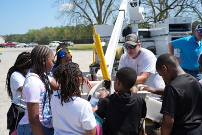 A group of young African American kids gather around a Roanoke Cooperative employee on Ag Safety Day