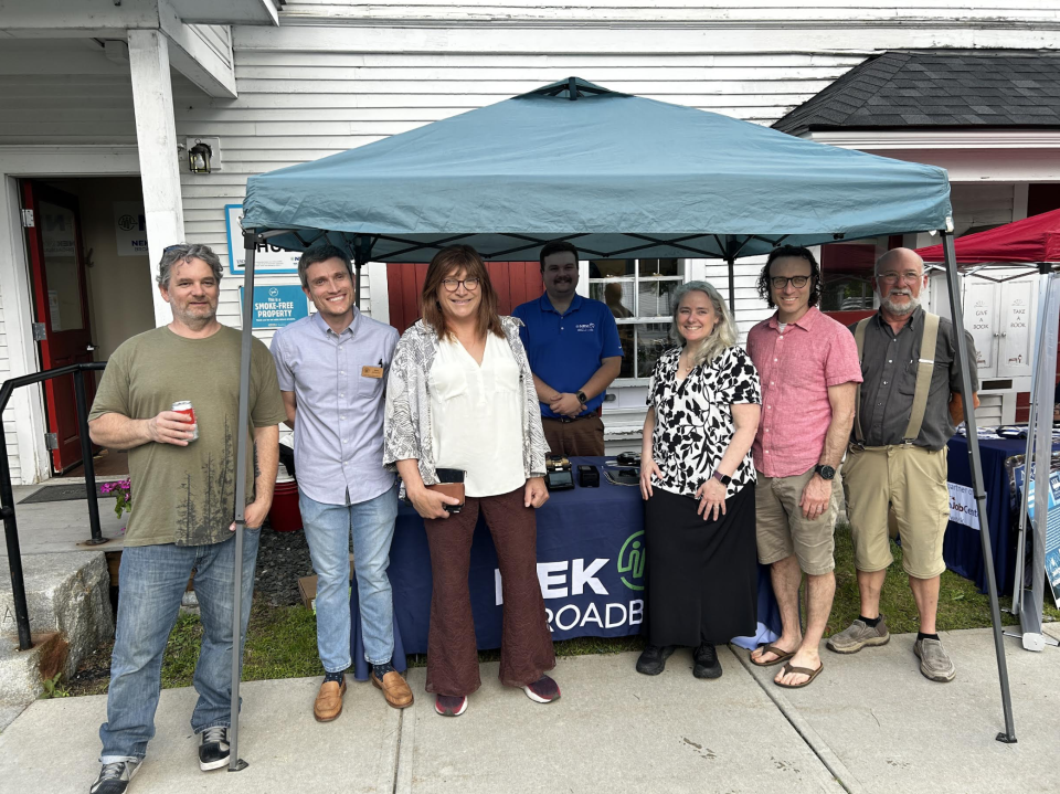 State and local broadband officials stand smiling outside of a tent at the Groton Connectivity Hub opening ceremony