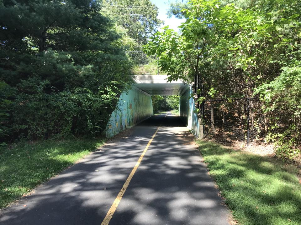A clear two lane roads leads to an overpass known as the Southwick Rail Trail Tunnel