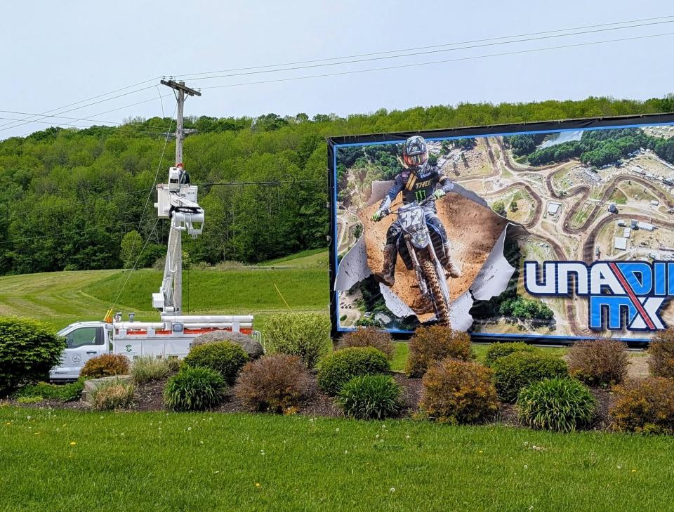 Sherburne Connect Bucket Truck working on utility pole next to a billboard advertising motorcross racing