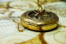 A vintage compass sits atop an antique map