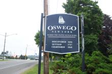 Sign on edge of road reads: Oswego New York, Where the water never ends"