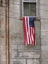 A US Flag hangs outside an apartment window behind utility wires
