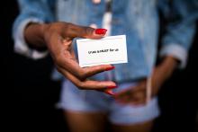An African American woman wearing a denim outfit holds a card in her hand that reads: trust is a must for us