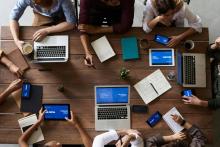 Aerial view of a group of people sitting around a table with laptops in front of each