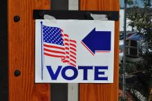 A sign that says "Vote" is taped to the side of a town building
